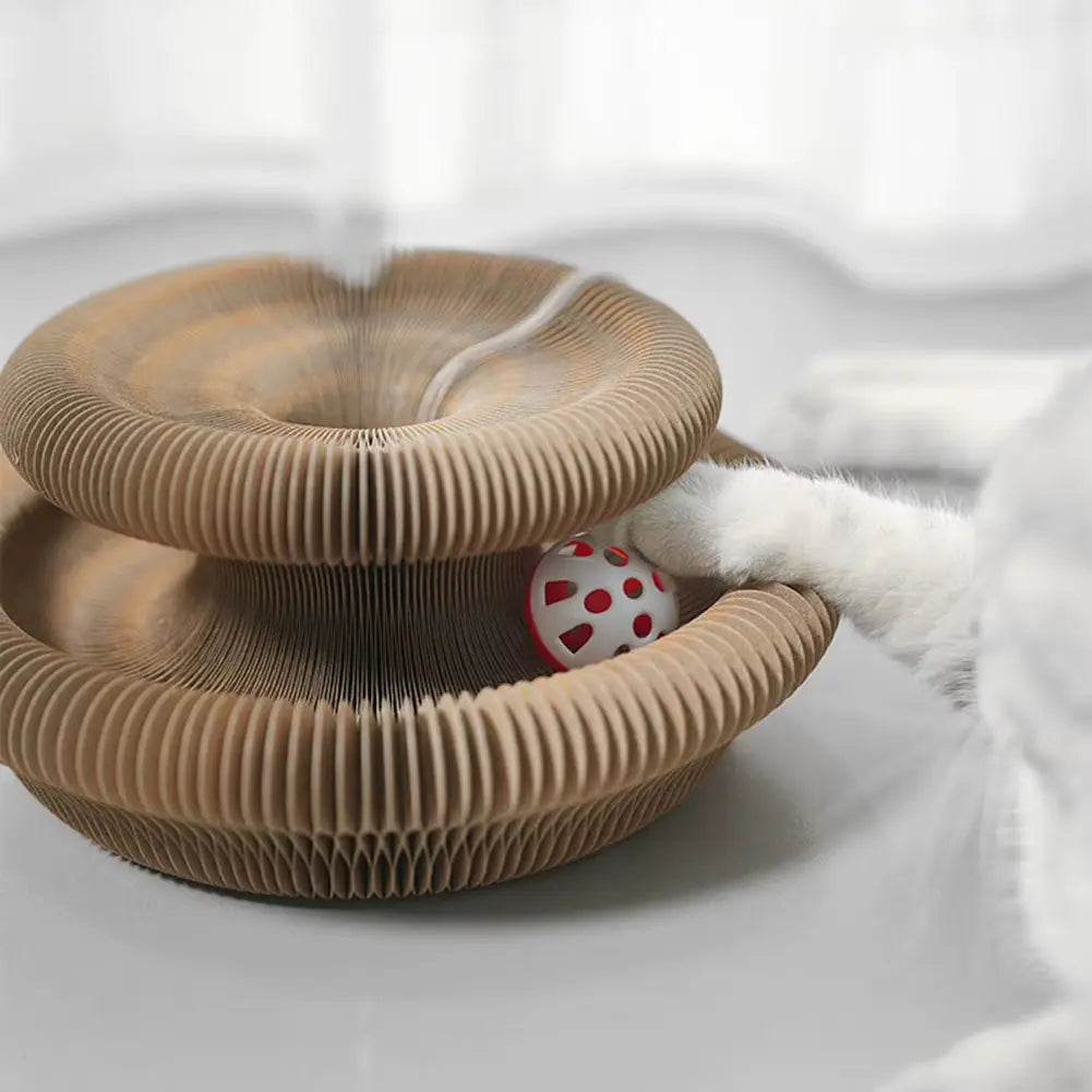 Griffoir interactif pour chat en carton ondulé pliable en forme d'accordéon, contenant une balle rouge ajourée au milieu.